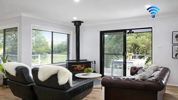 A modern living room with a fireplace, a sofa, a coffee table, and a view of the outdoors. - Hoddle Lane – rural views, fireplace and air conditioning (Robertson)