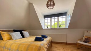 A bedroom with a bed, a window, a chair, and a radiator. - Charming Barn Conversion on Private Estate (Kilmarnock)