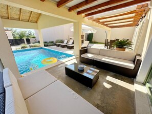 Ein Poolbereich mit einer Couch, Liegestühlen und einem Couchtisch.