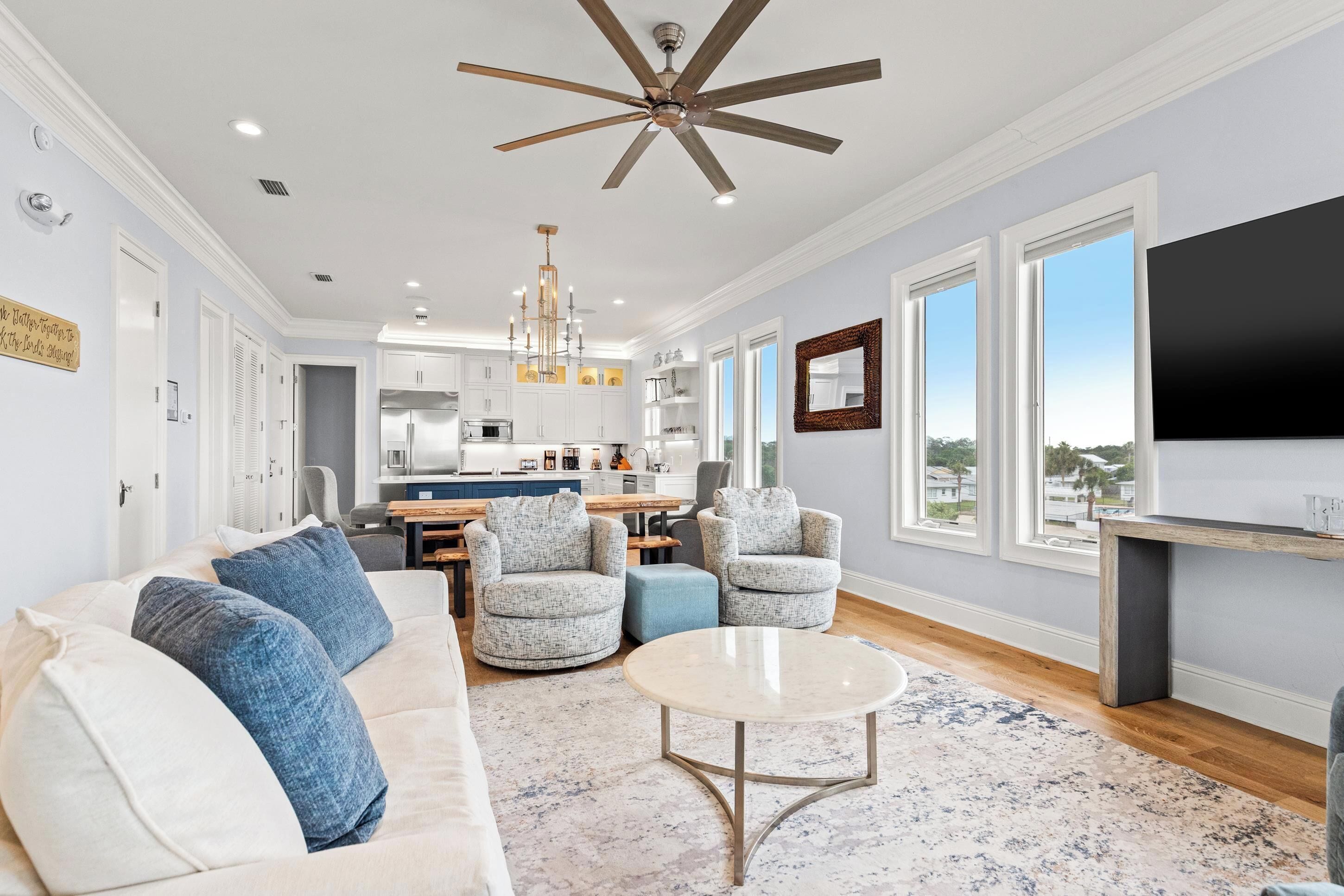 A spacious living room with a sofa, armchairs, a coffee table, and a TV.