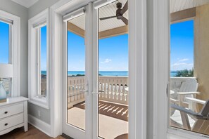 A room with a view of the ocean, a ceiling fan, and a white nightstand with a lamp. - Beach House - Stairway to Heaven By Panhandle Getaways (Panama City Beach)