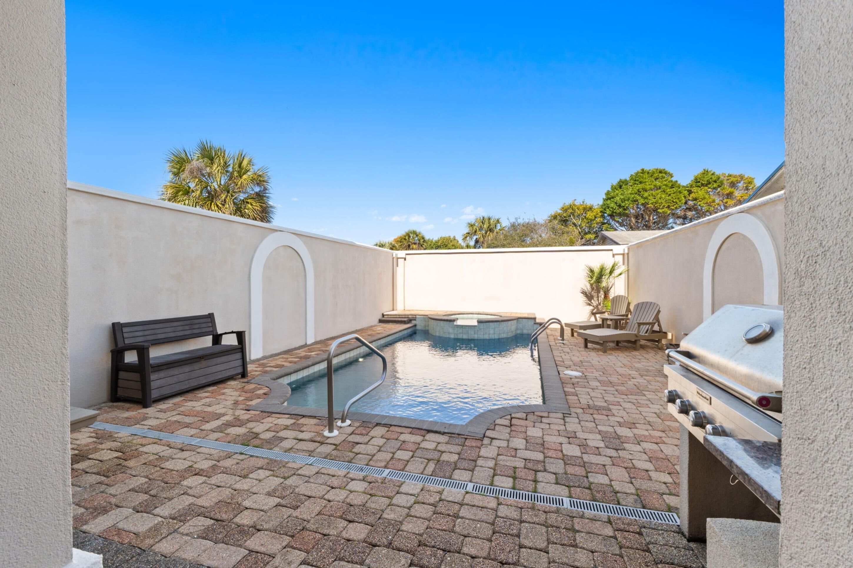 A backyard with a swimming pool, a barbecue grill, a bench, and outdoor seating.