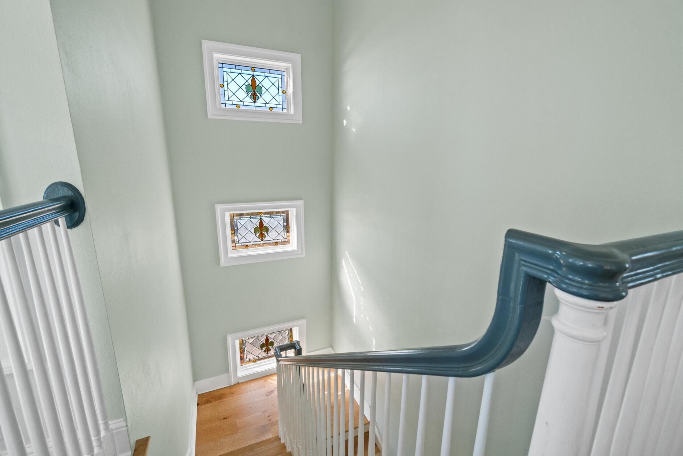 Un escalier avec des rampes blanches et un mur vert clair.