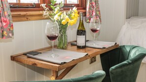 Una mesa de madera con dos copas de vino, una botella y un jarrón con flores.
