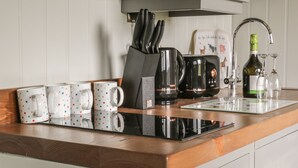 Una encimera de cocina con una cafetera, un bloque de cuchillos y una botella de vino.