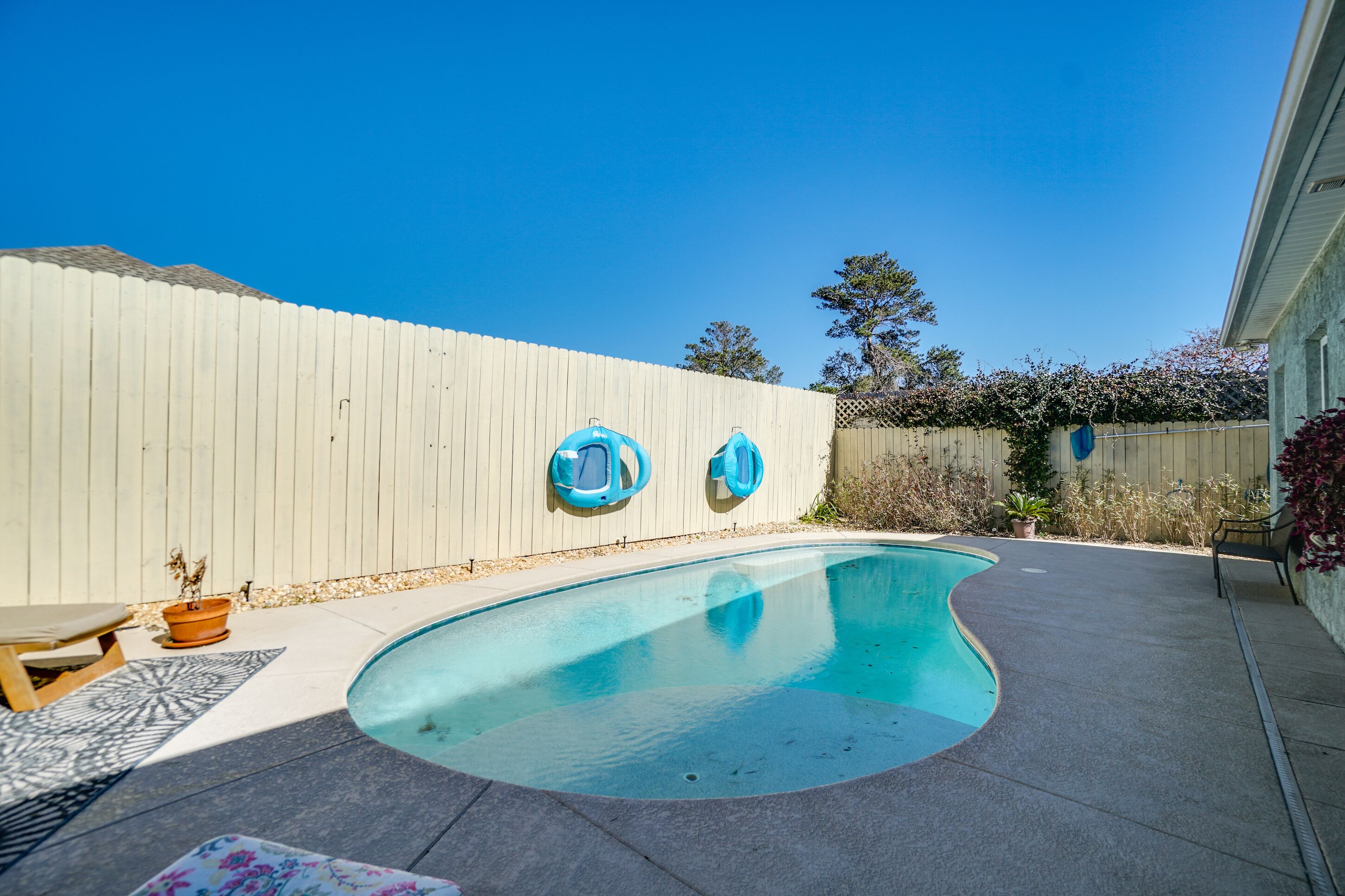 Um quintal com piscina, cerca de madeira e um banco.