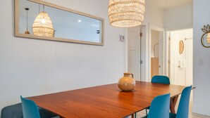 A dining area with a wooden table, blue chairs, a vase, a woven light fixture, and a mirror on the wall. - Beach House - The Starfish By Panhandle Getaways (Panama City Beach)