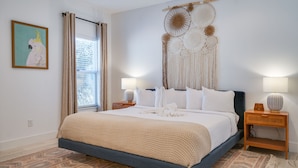 A bedroom with a bed, bedside lamps, a wall hanging, and a window with curtains. - Beach House - The Starfish By Panhandle Getaways (Panama City Beach)