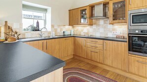 Eine moderne Küche mit Holzschränken, einer schwarzen Arbeitsplatte und Edelstahlgeräten.