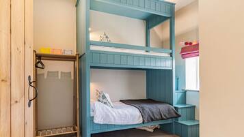 Una cama litera con un armario de madera y una ventana con cortinas.