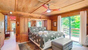 A wooden cabin bedroom with a bed, a ceiling fan, and a view of the outdoors. - Mars Hill Cabin w/ Pool Table ~ 2 Mi to Wolf Ridge (Mars Hill)
