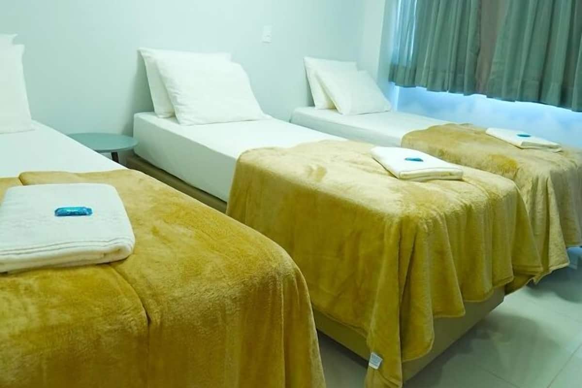 Habitación de hotel con dos camas, una mesita redonda y un ventanal grande con cortinas.