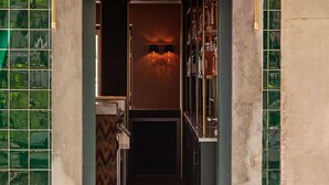 Une entrée étroite surmontée d’un auvent vert, un mur recouvert de carreaux sur un côté et un plancher en bois à l’intérieur.
