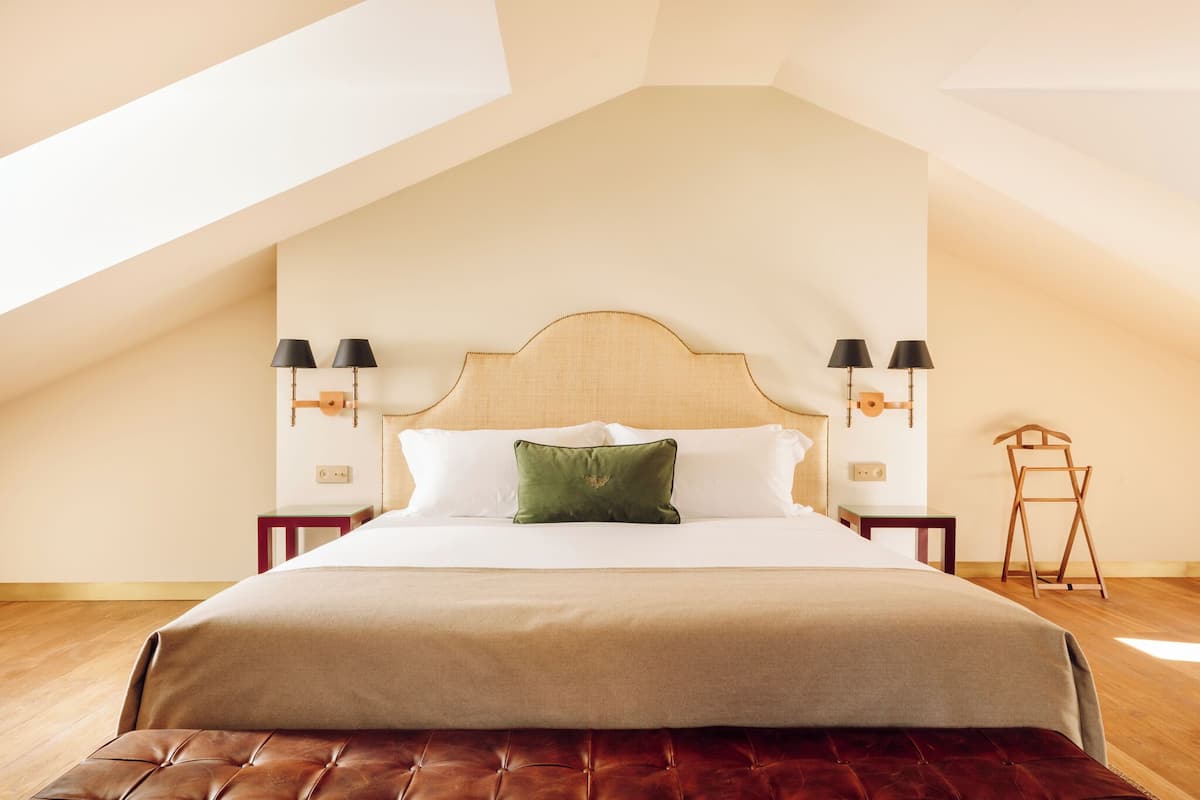 Una camera da letto con un letto grande, due lampade da comodino, una testiera in legno e una sedia di legno.