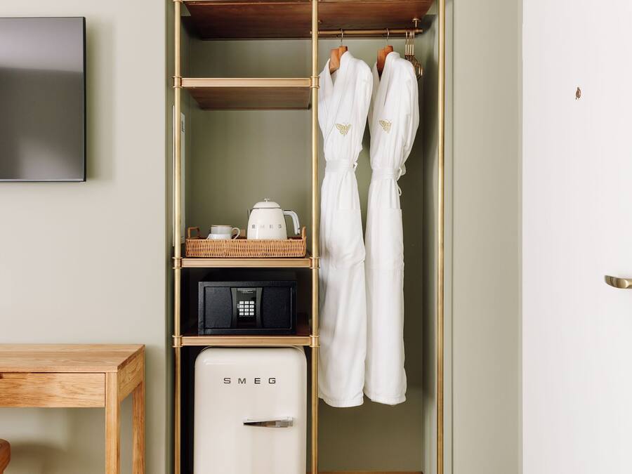 Una habitación de hotel con armario, televisión, cafetera y minibar.