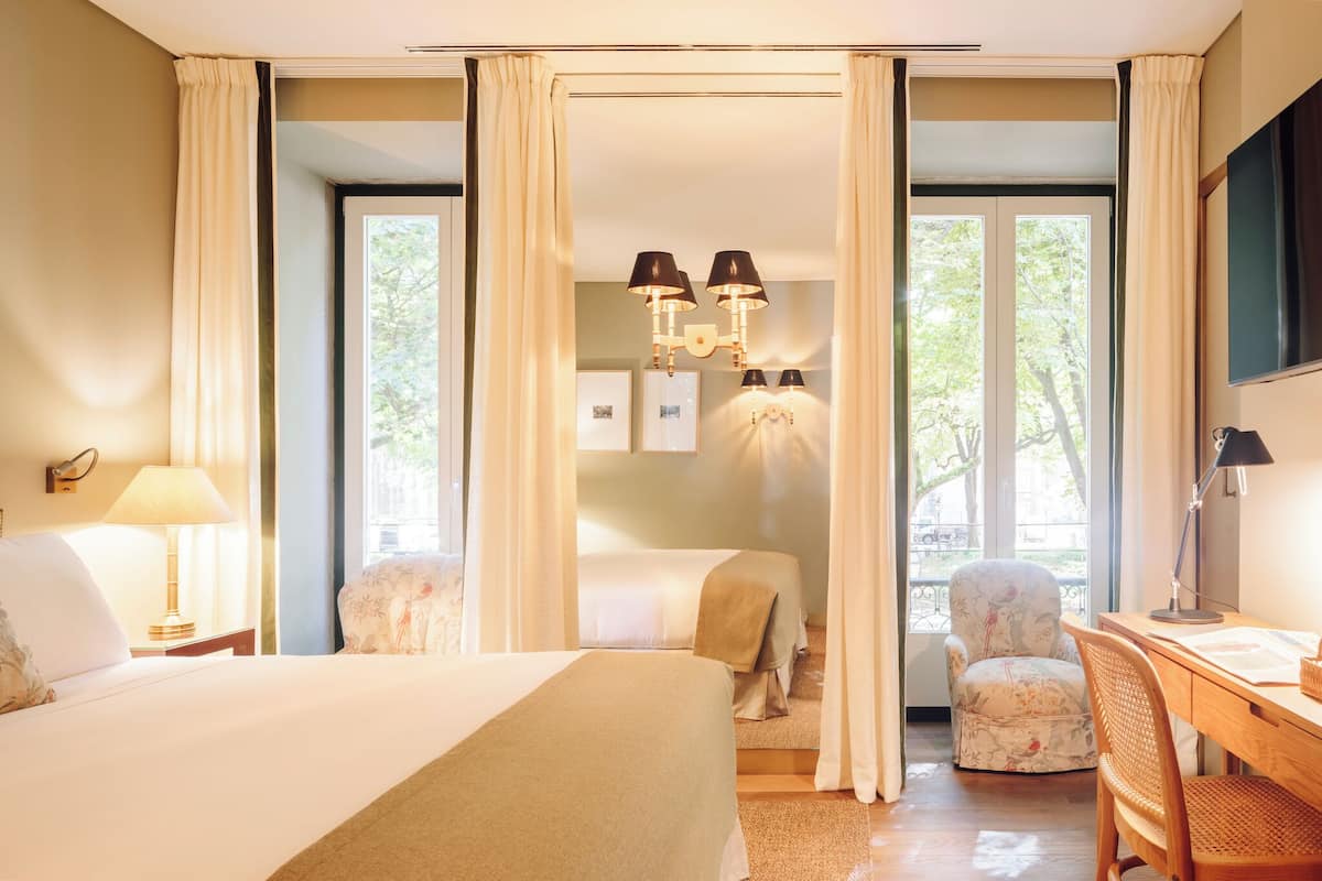Una camera d'albergo con un letto grande, due poltrone, una scrivania e un lampadario.