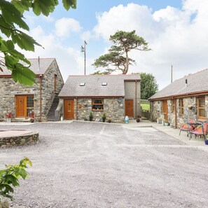A stone building with a gravel driveway, wooden doors, and a tree in the background. - Barn conversion at the old Watermill - Snowdonia & Zip Line close by. (Pentir)