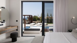 Ein modernes Hotelzimmer mit einem großen Bett, einem Schreibtisch und Blick auf einen Swimmingpool sowie eine Außenbereich-Sitzgelegenheit.