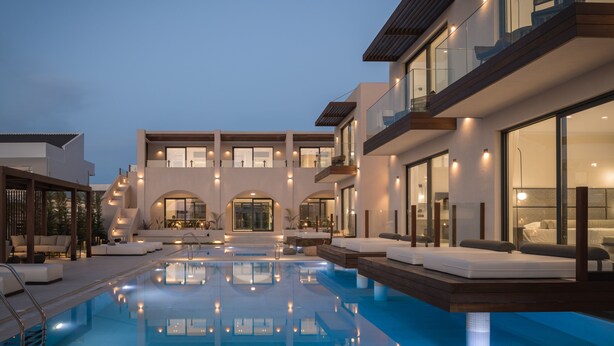 Ein moderner Poolbereich mit mehreren Liegezonen und einem großen Gebäude mit Balkonen und großen Fenstern.