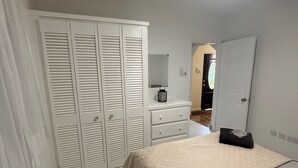 Un dormitorio con cama, armario, cómoda, espejo y ventilador de techo.