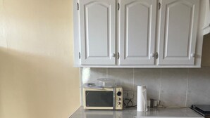 Una cocina con armarios blancos, un microondas y una encimera.
