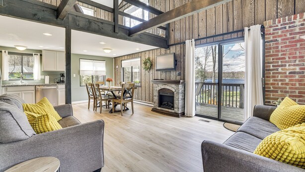 A spacious living area with a fireplace, wooden beams, and a dining area with a table and chairs. - Pocono Lake Home w/ Fire Pit: Walk to Ski Hill! (Pocono Lake)