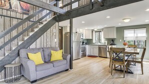 A modern interior with a staircase, grey sofa with yellow cushions, wooden dining table, and white cabinets. - Pocono Lake Home w/ Fire Pit: Walk to Ski Hill! (Pocono Lake)