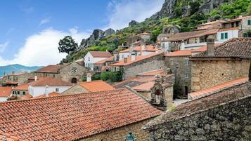 Un pueblo en la ladera de una colina con edificios de tejados de terracota, muros de piedra y una iglesia destacada.