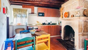 Una cocina rústica con armarios de madera, una chimenea de piedra y un comedor con mesa y sillas de madera.