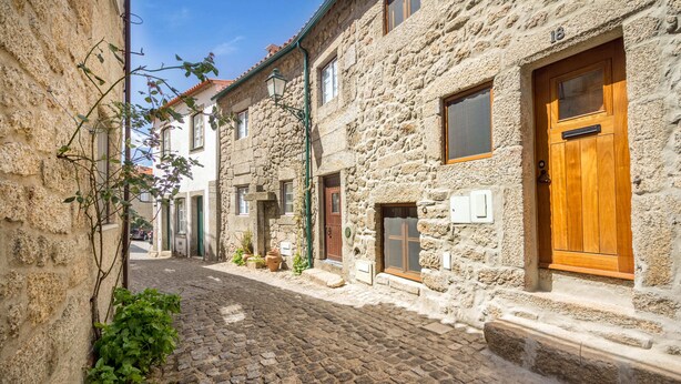 Una calle adoquinada flanqueada por edificios de piedra, con una puerta de madera y una ventana a la derecha.