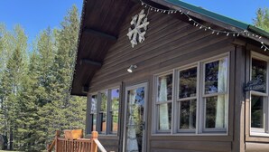 Eine Holzhütte mit Veranda, Steinstufen und einer Bärenstatue.