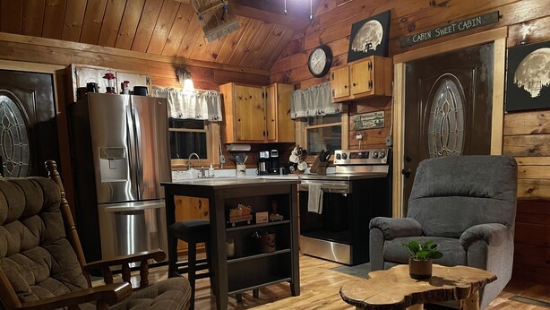 Ein gemütliches Blockhaus-Interieur mit Holzböden, einem Essbereich, einer Küche mit modernen Geräten und einer bequemen Sitzecke.