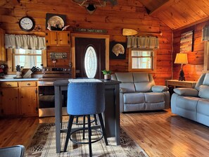 Ein Ferienhaus-Interieur mit Holzvertäfelung, einer Essecke, einer Couch und einer Küche.