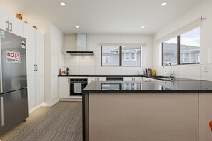 A modern kitchen with a stainless steel refrigerator, a no-smoking sign, a built-in oven, and a large window.
