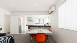 Uma cozinha moderna com armários brancos, uma ilha central com pia e um espaço de refeições com mesa e cadeiras.