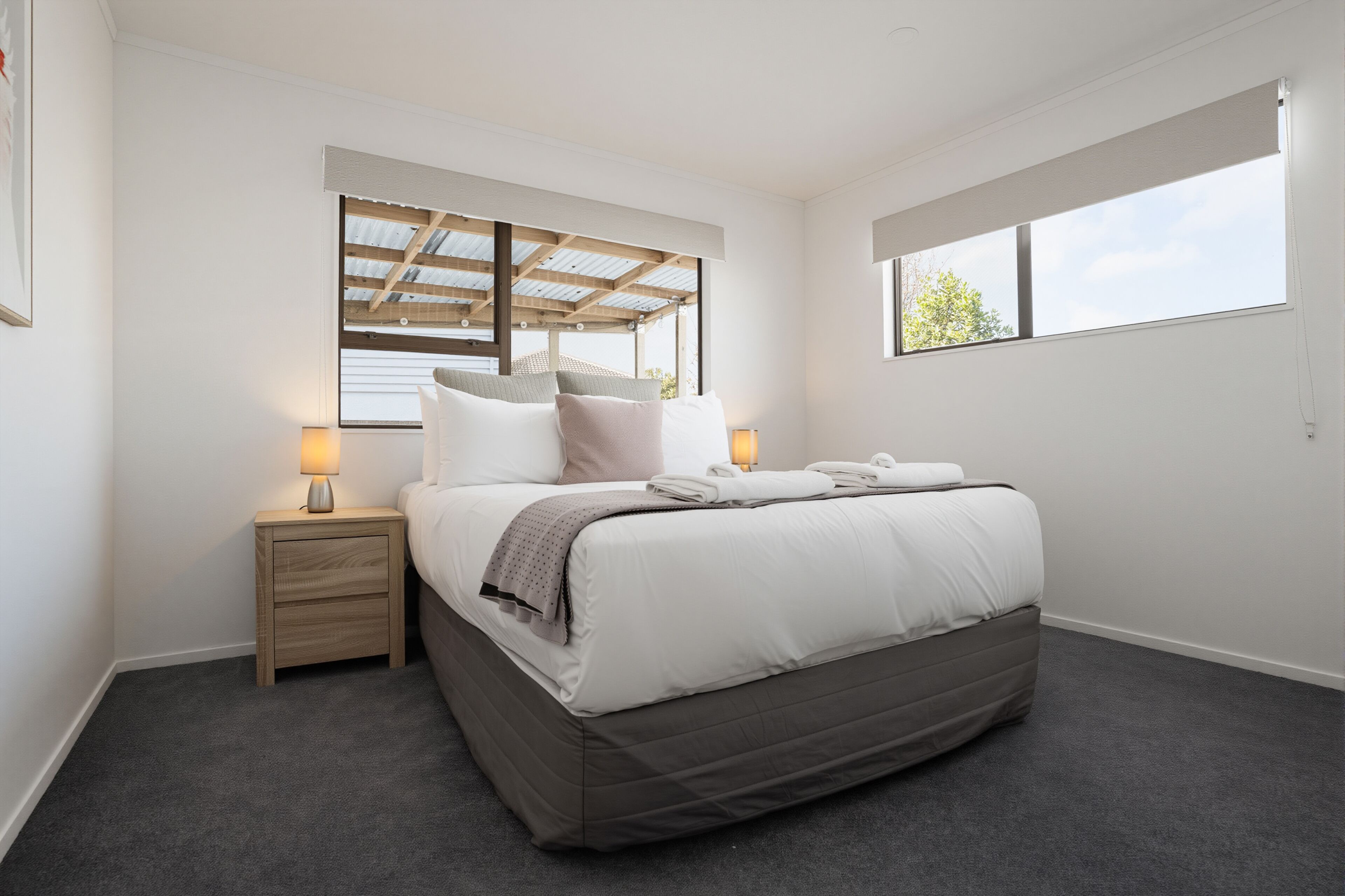 A bedroom with a bed, bedside tables, a window, and a ceiling with a skylight.