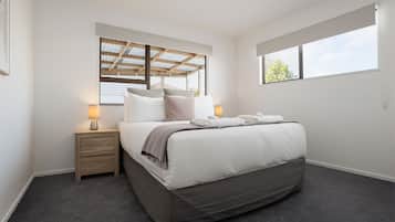 A bedroom with a bed, bedside tables, a window, and a ceiling with a skylight.