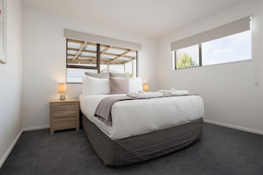A bedroom with a bed, bedside tables, a window, and a ceiling with a skylight.