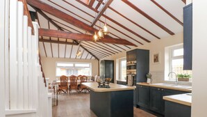 Une cuisine moderne avec des meubles de couleur sombre, un îlot central et un coin repas doté de chaises en bois.