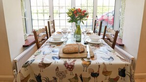 A dining table set with plates, glasses, and a loaf of bread, surrounded by chairs.