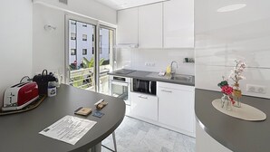 A modern kitchen with white cabinets, a black countertop, and a view of the outside. - Cannes: Pointe croisette 1 bdr apartment 100 m to beaches - cute balcony (Cannes)
