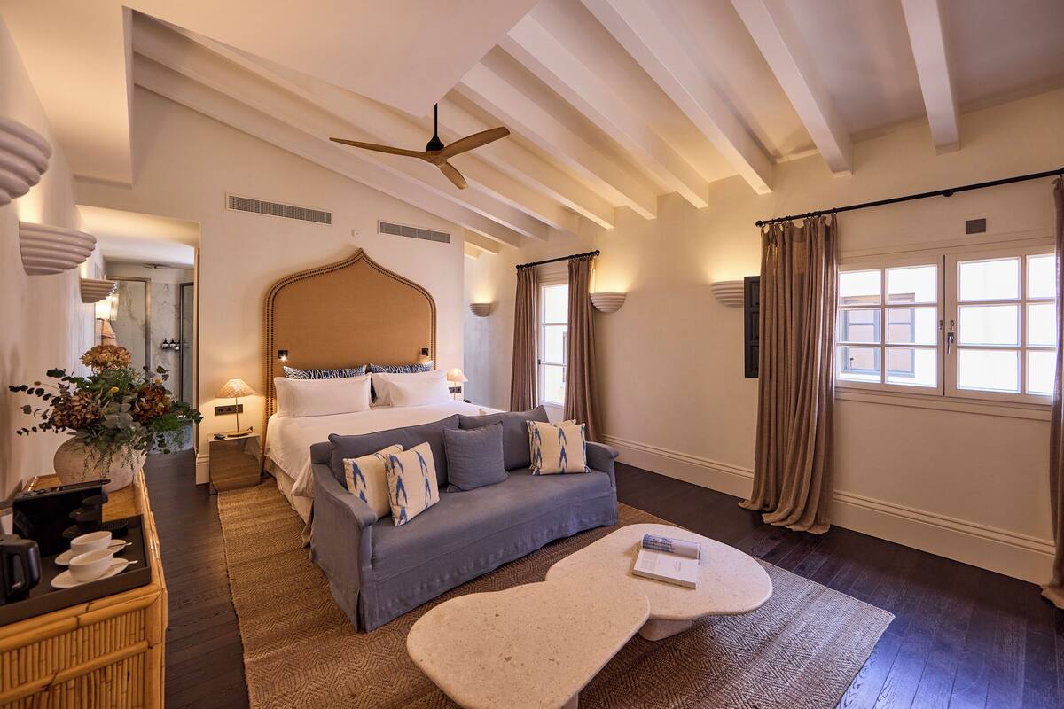 Een hotelkamer met een bed, een sofa, een salontafel en een plafondventilator.