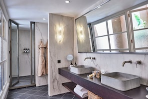 Uma casa de banho moderna com duas lavatórios, um espelho grande e uma cabine de duche.