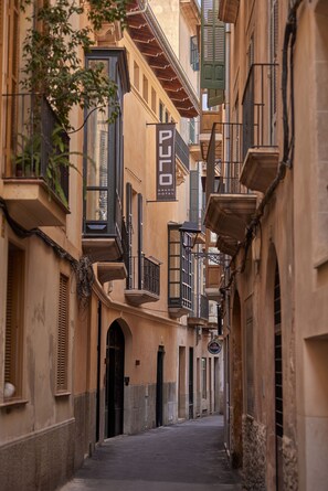 Uma rua estreita com edifícios com varandas e persianas.