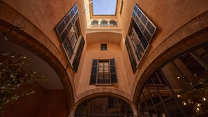 Une cour intérieure agrémentée d’arcades, d’une verrière et offrant une vue sur le ciel.