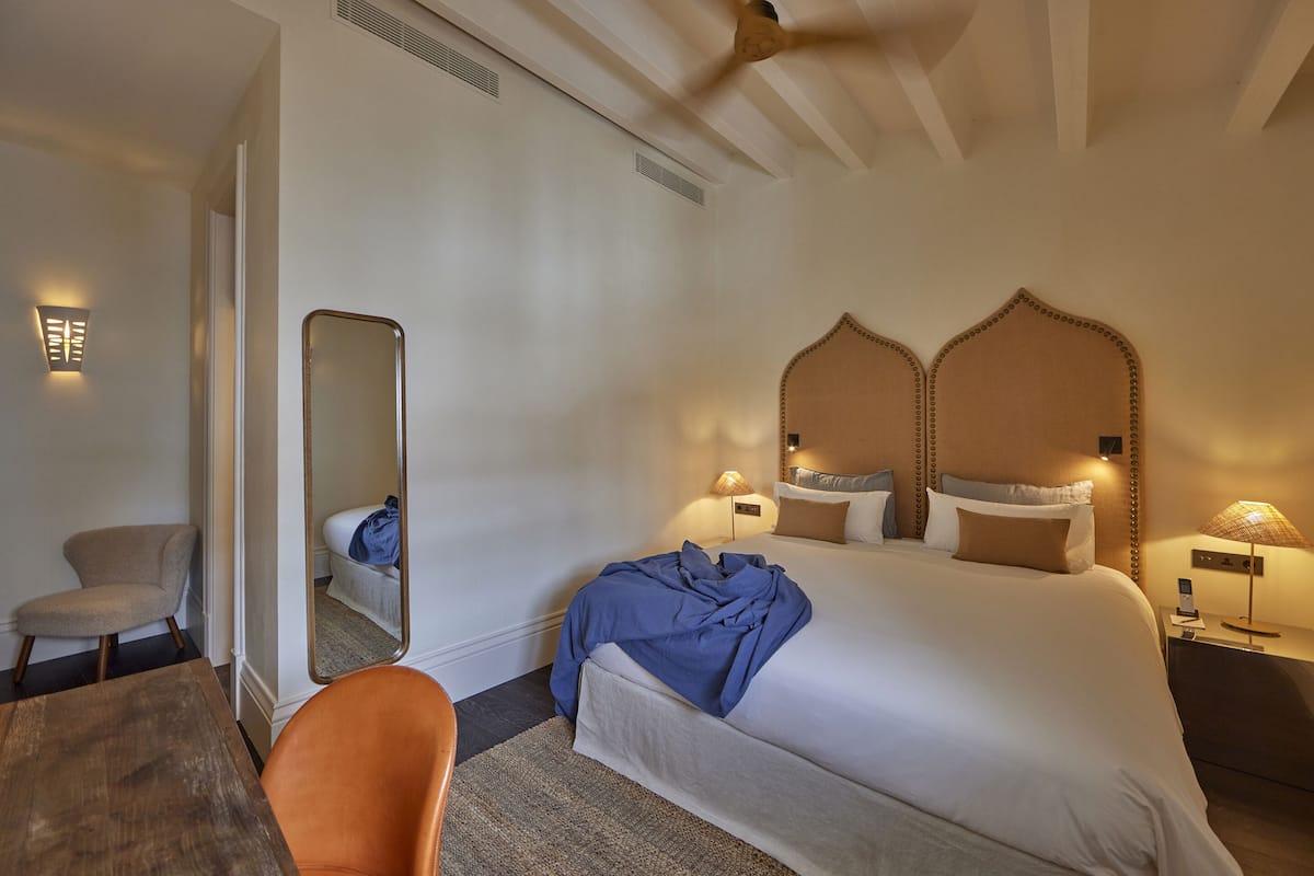 Een hotelkamer met een groot bed, een stoel, een bureau en een spiegel.