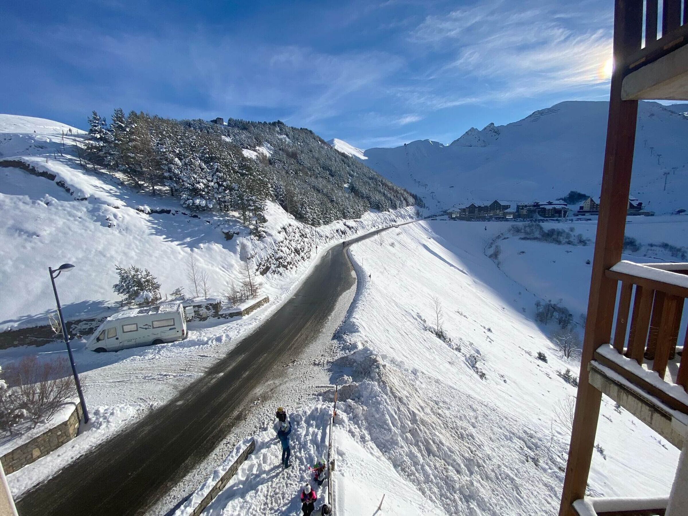 A snow-covered road with a wooden fence on one side and a building on the other.