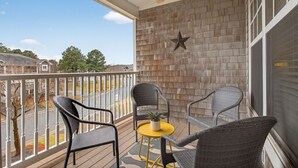 A balcony with wicker chairs, a small round table, and a potted plant.