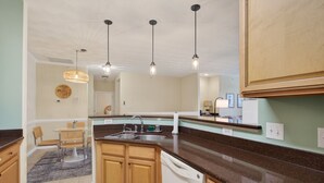 A kitchen with wooden cabinets, a dishwasher, a sink, and pendant lights.