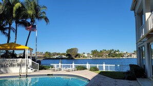 Piscina com toldo amarelo, vista para a água e um edifício com varanda.